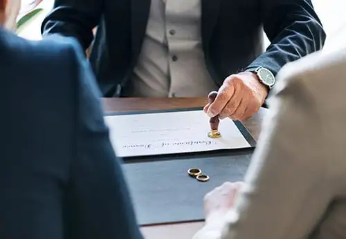 Couple sitting at table for uncontested divorce signing with judge gavel and wedding ring.