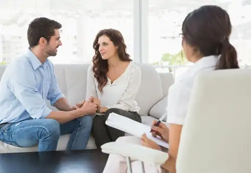 A couple engaged in a conversation while seated on a couch in front of lawyer