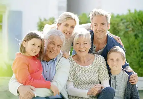 A family of six sitting on a bench, enjoying each other's company in a park.